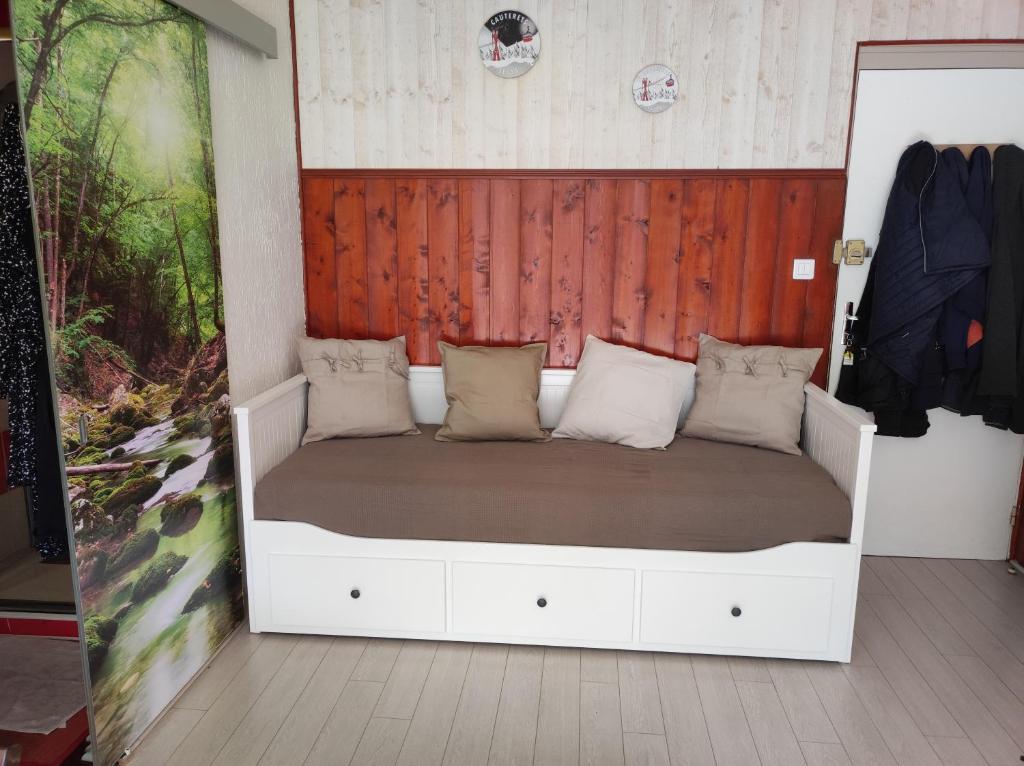 - un lit blanc dans une chambre dotée d'un mur en bois dans l'établissement Hyper centre, excellent emplacement, à Cauterets