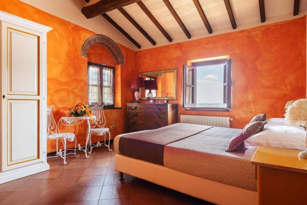 sypialnia z pomarańczowymi ścianami oraz łóżkiem i stołem w obiekcie Agriturismo - Collina Toscana Resort w mieście Monsummano Terme