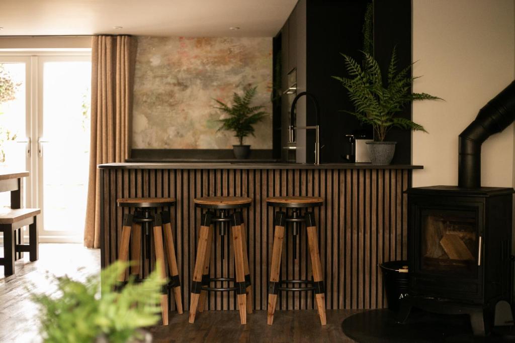 a kitchen with a bar with four stools at Akasha Spa Retreat Cottage in Welton