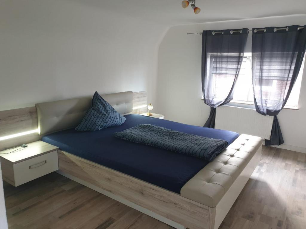a bedroom with a bed with blue sheets and two windows at Ferienhaus Käthe-Kollwitz in Eckernförde