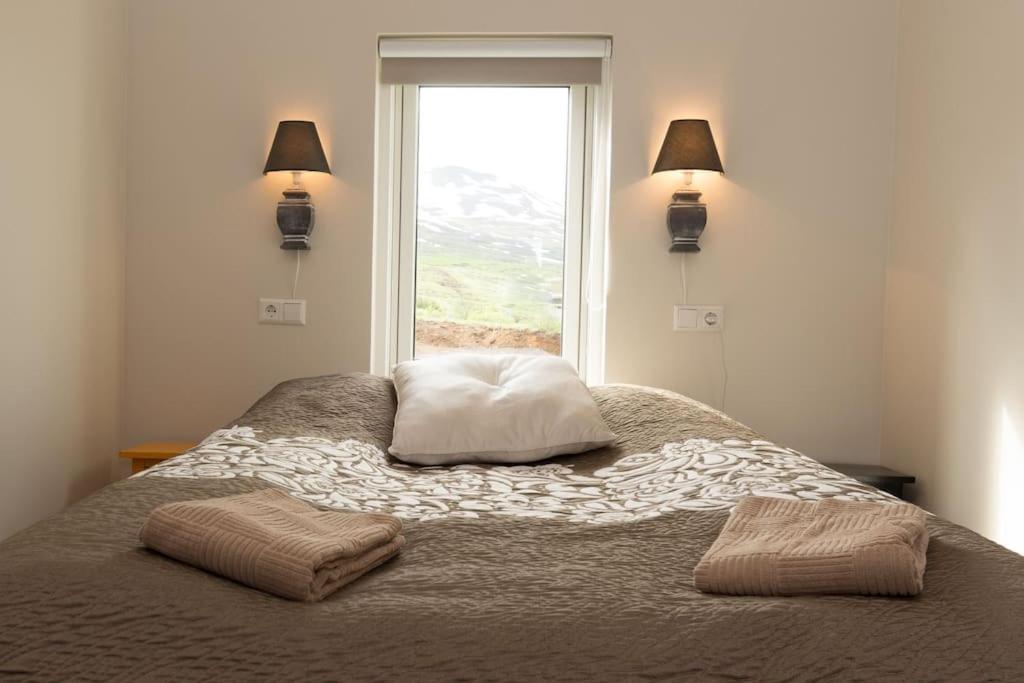 um quarto com uma cama com duas almofadas e uma janela em Private cottage, elegance & amazing view em Akureyri