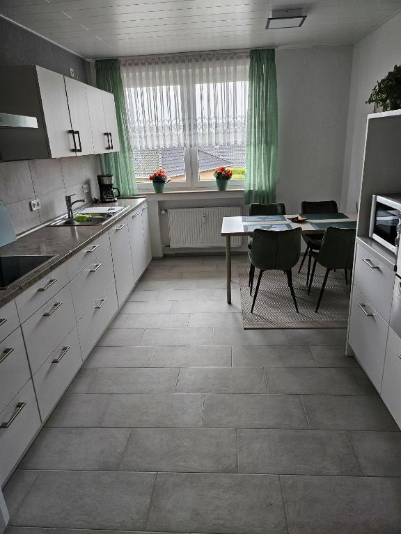 eine Küche mit weißen Schränken und einem Tisch mit Stühlen in der Unterkunft Ferienwohnung  Monteurwohnung - b63890 in Bremerhaven