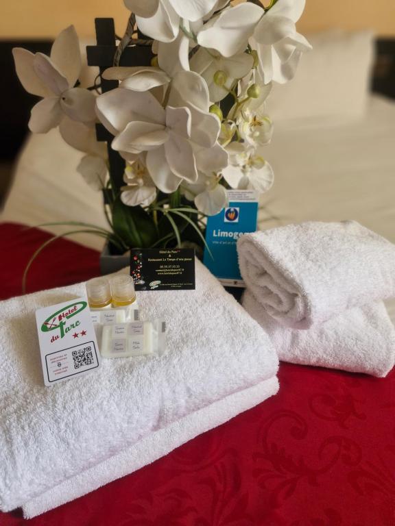 a table with towels and a vase with flowers at Hôtel du Parc Limoges & Restaurant "Le temps d'une pause" in Limoges