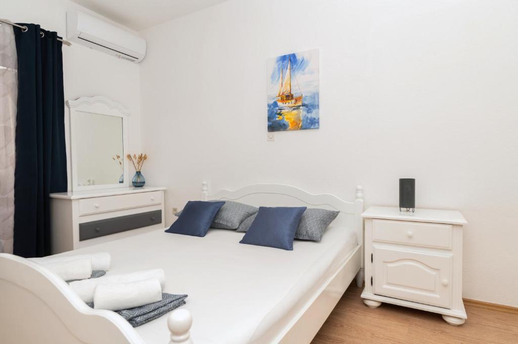 a white bed with blue pillows in a room at Apartments Marsela in Tučepi
