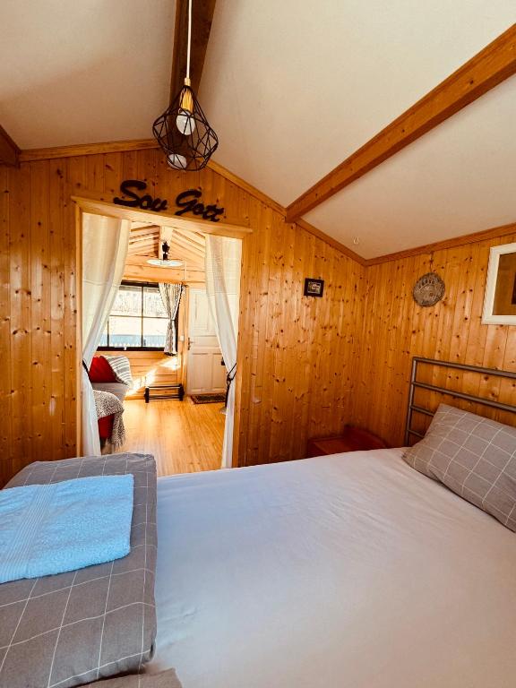 a bedroom with a bed in a room with wooden walls at The Hideout Log Cabin- 2km to Klarälvsbanan and swimming area in Munkfors