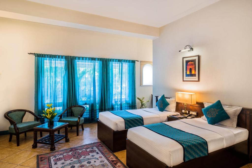 two beds in a hotel room with blue curtains at Home@F37 Kailash Colony Metro in New Delhi