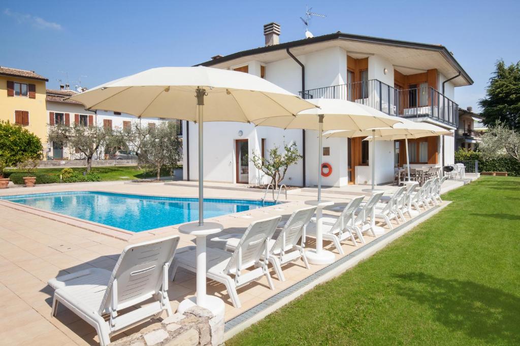 a group of chairs and umbrellas next to a pool at Ca' Le Terrazze With Pool in Garda