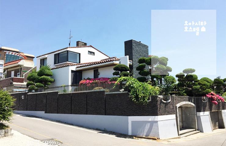 a white house with a black fence and plants at Oasita Hostel in Gwangju