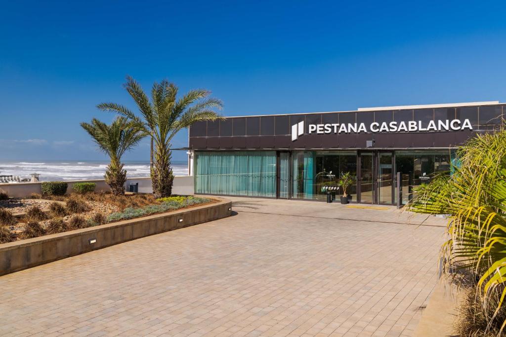 ein Gebäude am Strand mit einer Palme in der Unterkunft Pestana Casablanca, Seaside Suites & Residences in Casablanca