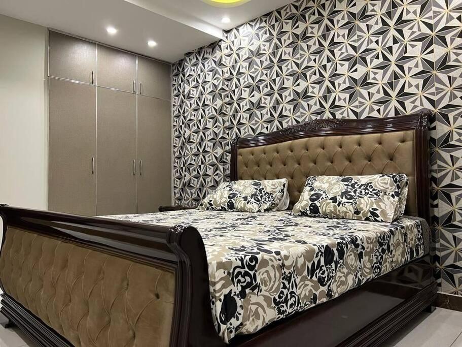 ein Schlafzimmer mit einem Bett und einer Wand in der Unterkunft 103-NEXT INN Tailored to your Highest Standards in Lahore