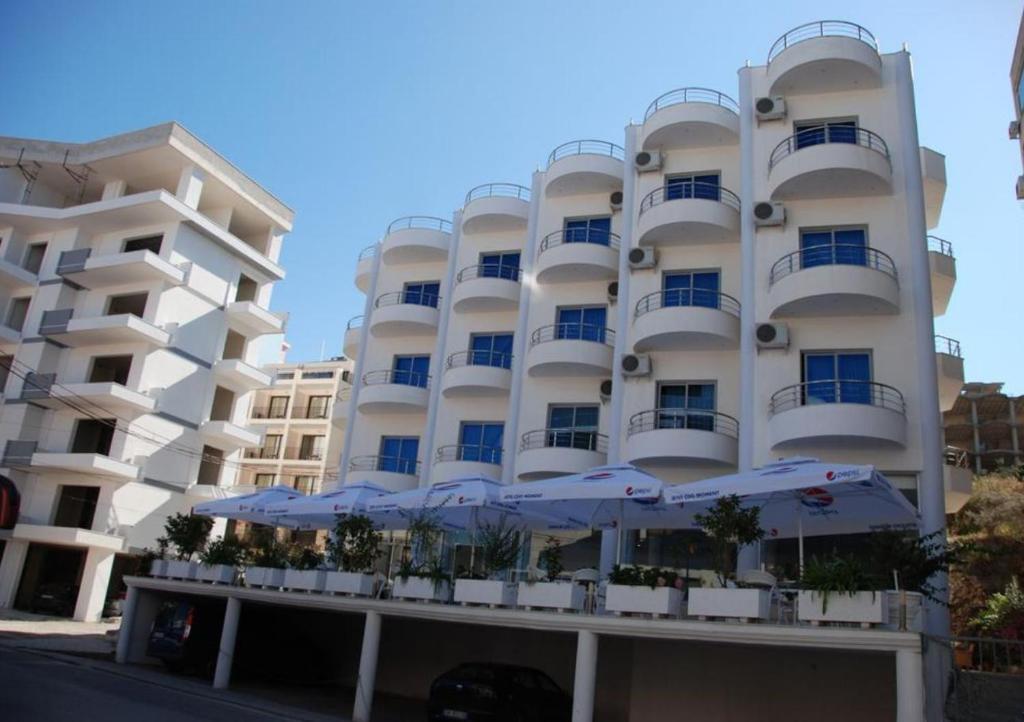 un edificio blanco con sombrillas delante en Arel Hotel, en Sarandë