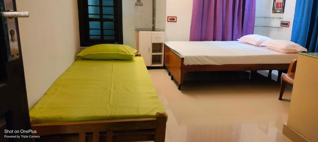 um quarto com duas camas e um colchão verde em Parthasarathy Home stay em Trivandrum