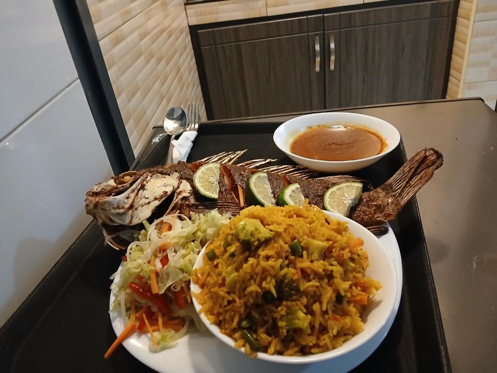 a tray with a plate of food and a bowl of soup at Lovana apartments and hotel in Gulu