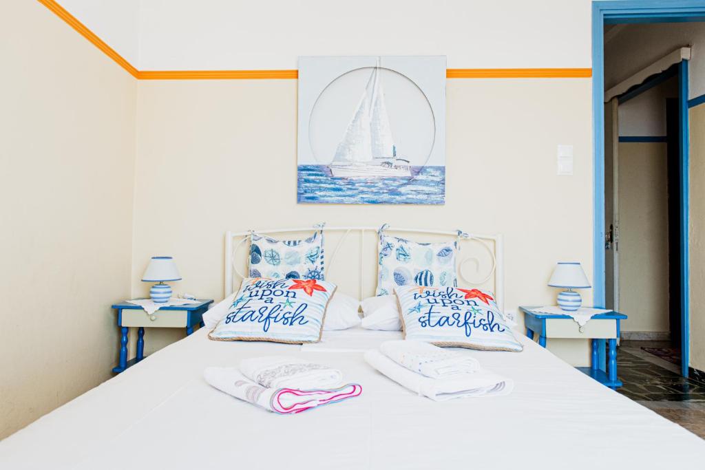 a bedroom with a white bed with blue and white pillows at Mavromati Rooms in Kivérion
