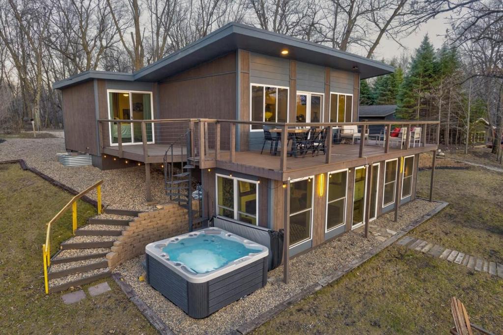 uma pequena casa com uma banheira de hidromassagem no quintal em Lakefront Retreat~Hot Tub~Game Room~Fire Pit~ BBQ em Spirit Lake