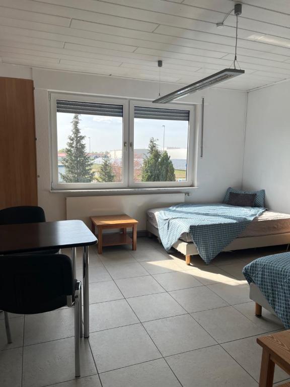 een slaapkamer met een bed, een tafel en 2 ramen bij Zimmervermietung Conny in Elsterwerda