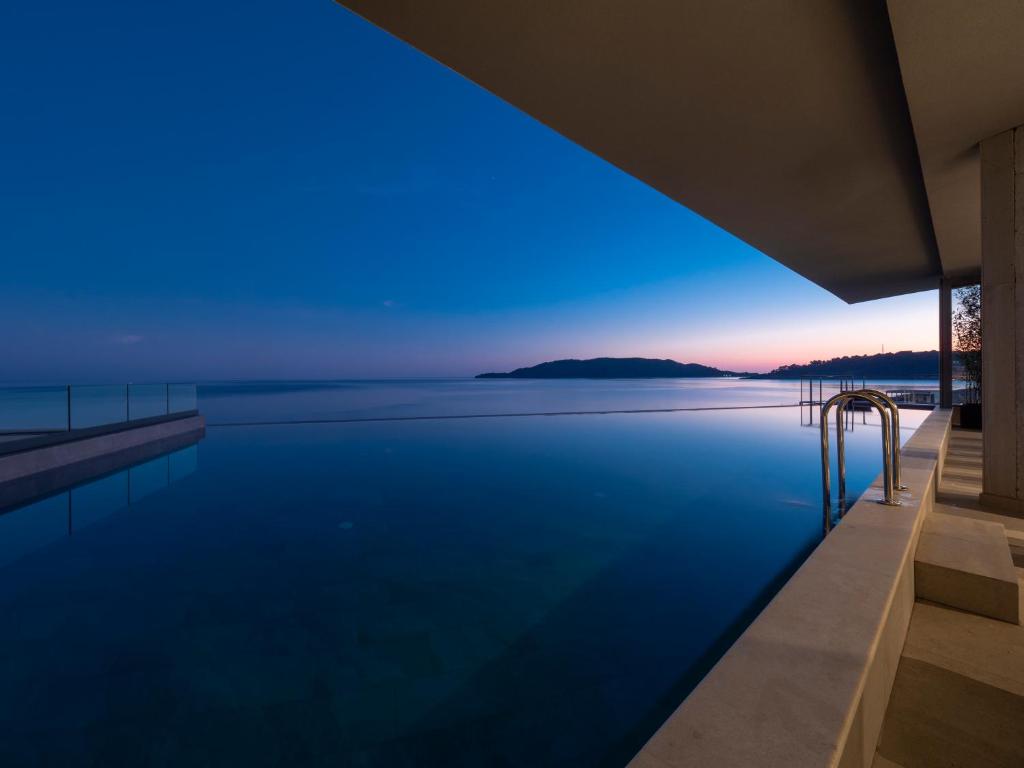 a pool with a view of the ocean at dusk at Sea Star Budva in Budva