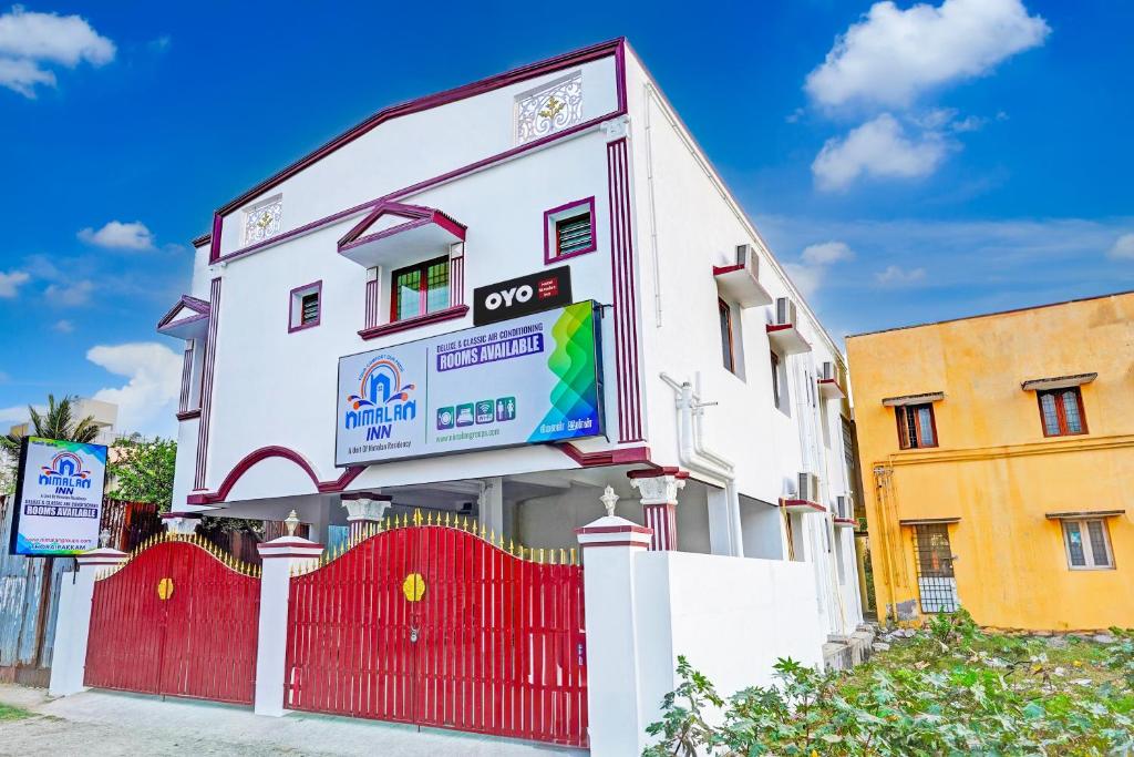 a white building with a red fence in front of it at OYO Nimalan INN in Chennai