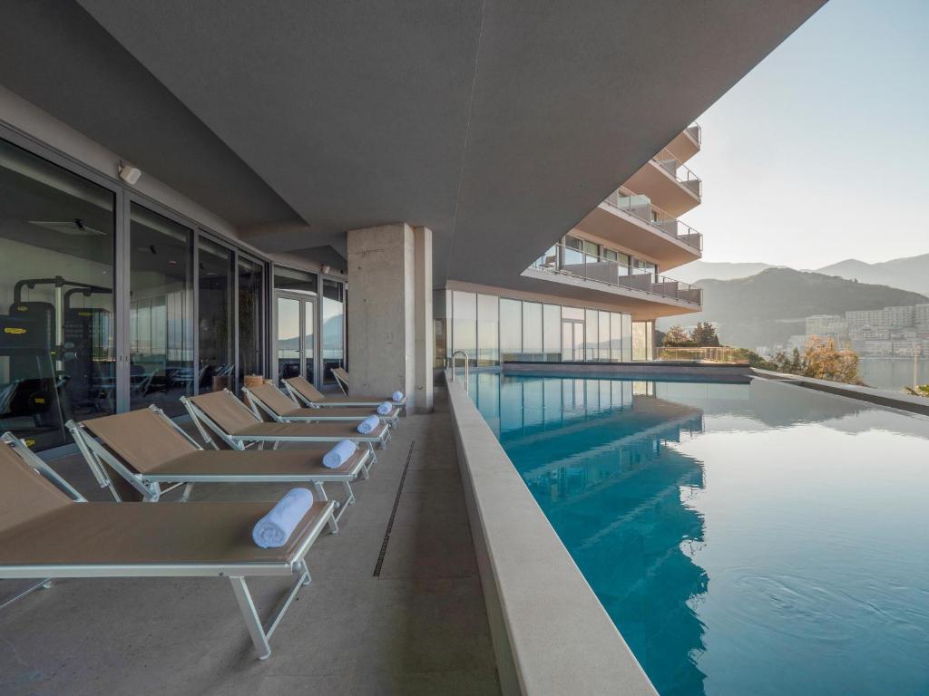 a swimming pool with lounge chairs next to a building at Sea Star Budva in Budva