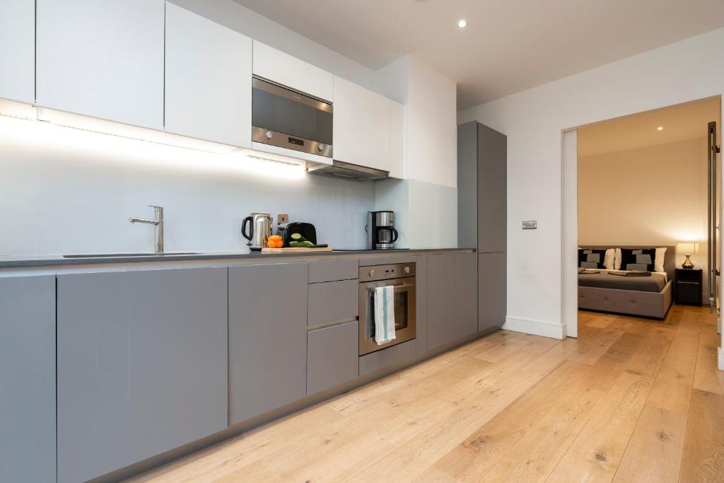 a kitchen with white cabinets and a wooden floor at Camden Town Apartments in London