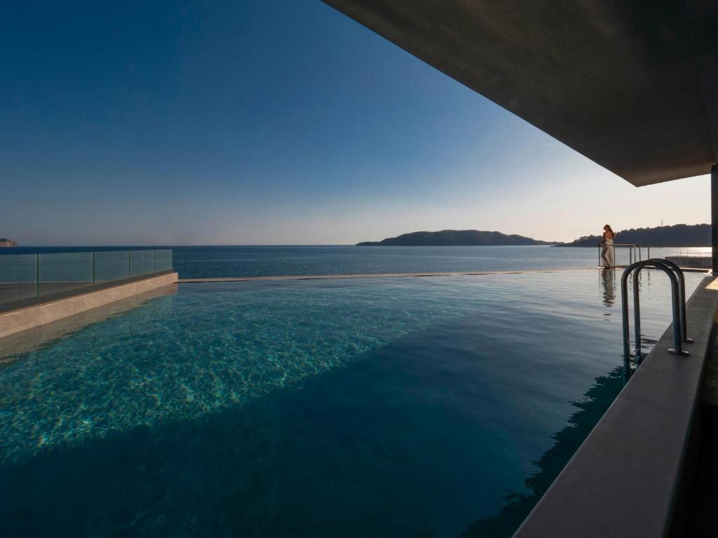 a woman standing in a swimming pool overlooking the water at Sea Star Budva in Budva