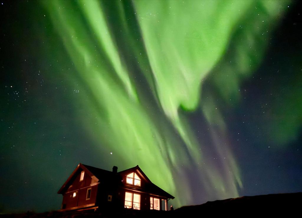 a house with the aurora in the sky at Moderne hytte på fantastiske Gimsøy i Lofoten in Gimsøy