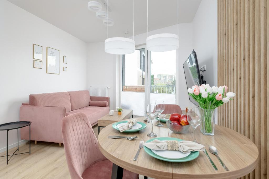 a living room with a table and a pink couch at Stylish Apartment with Balcony and Garage in Świnoujście by Renters in Świnoujście