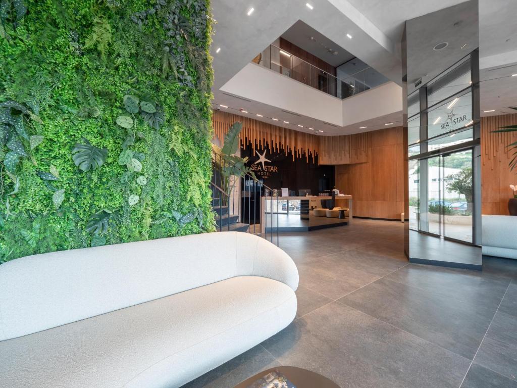 a white couch in a lobby with a green wall at Sea Star Budva in Budva