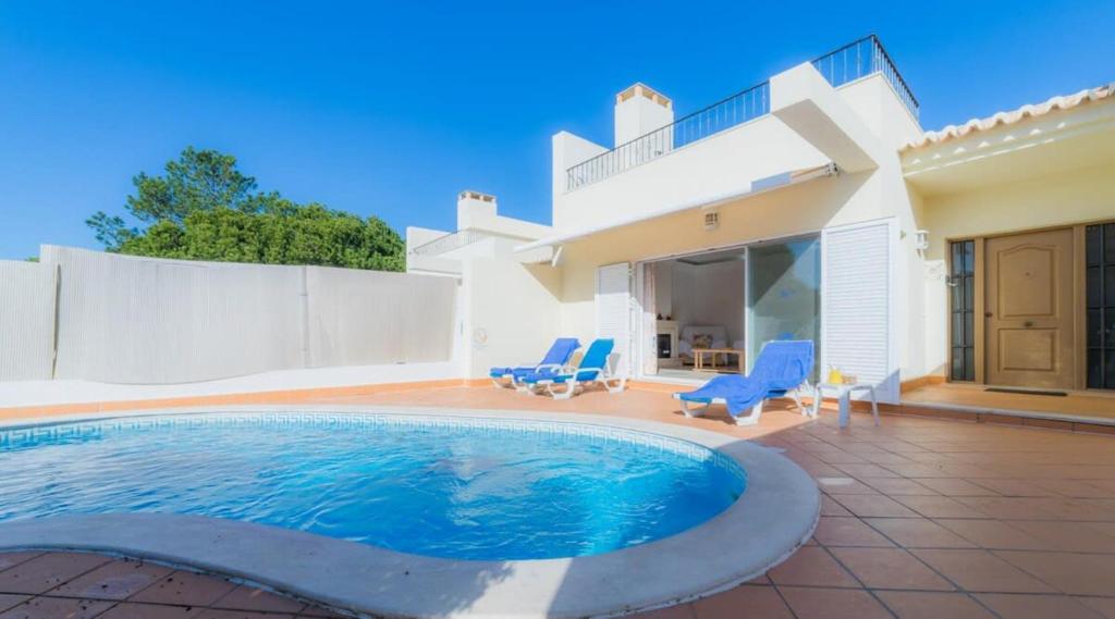 a house with a swimming pool and two blue chairs at Villa Tulipa - luxury golfing resorts in Almancil