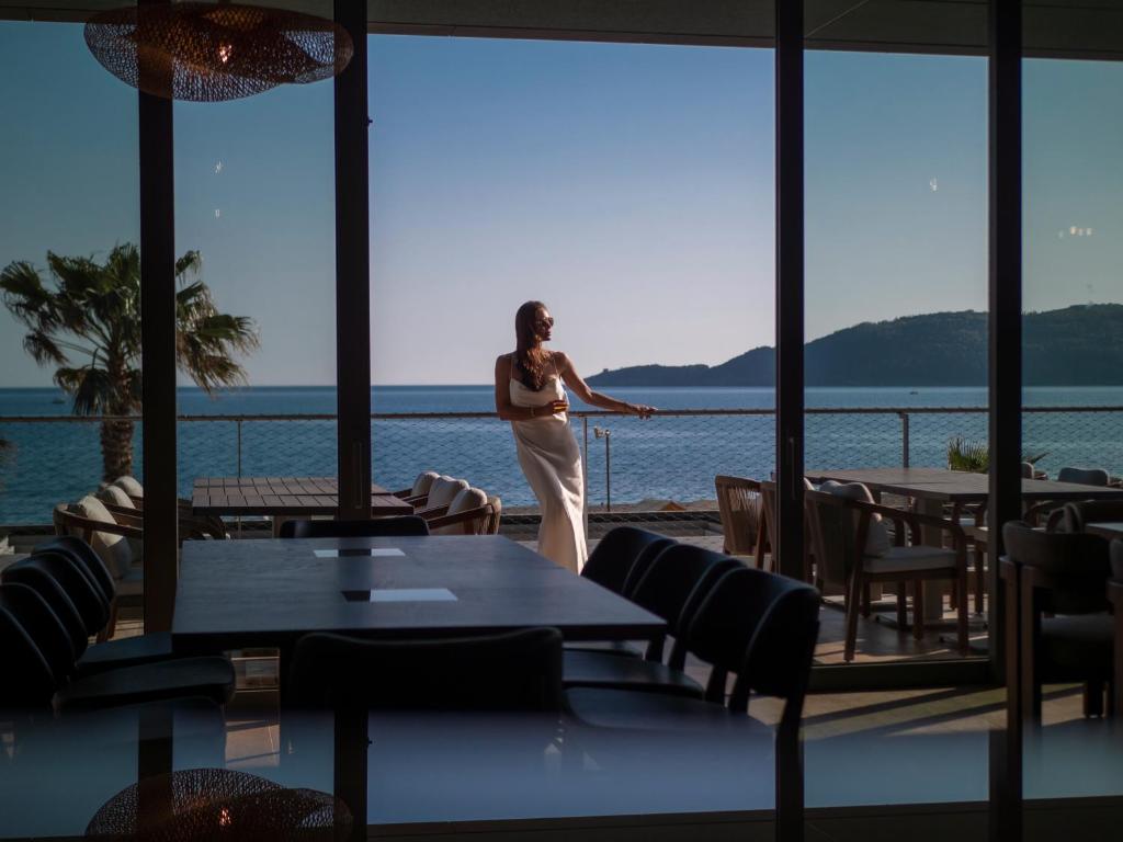 a woman standing in a room with a view of the water at Sea Star Budva in Budva