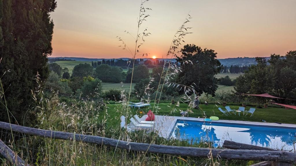 a pool in a field with a sunset in the background at Siena House in Torrita di Siena