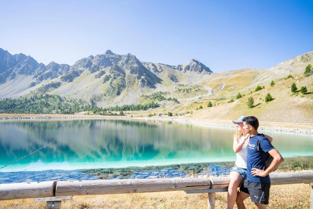 a man sitting on a fence next to a lake at Villages Clubs du Soleil - VARS in Vars