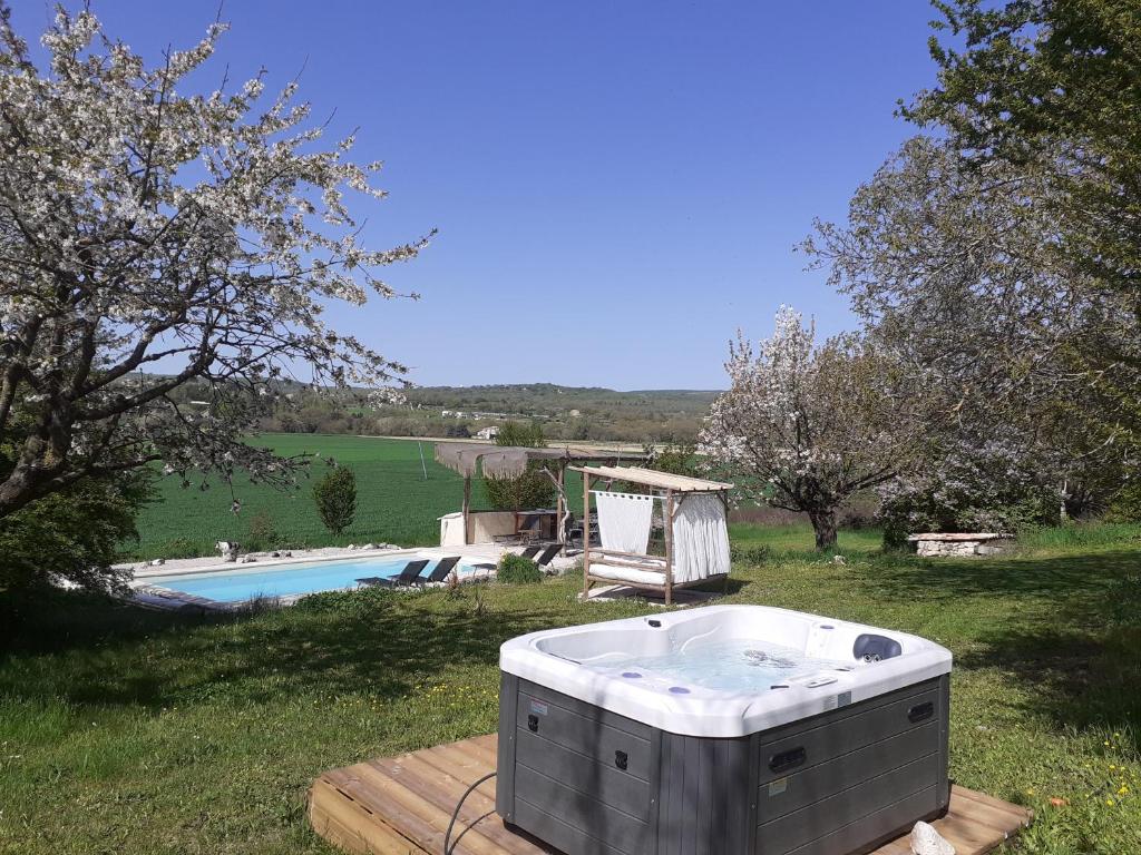 een hot tub op een terras naast een zwembad bij Le Sens des Merveilles in Mane