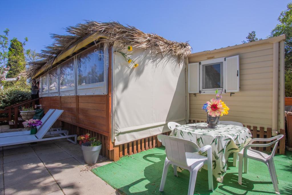 une petite maison avec une table et des chaises sur une terrasse dans l'établissement Mobilhome Puget-sur-argens, à Puget-sur Argens