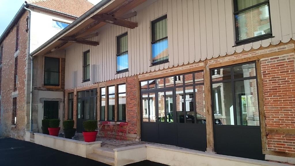 a brick building with glass windows and potted plants at L'Atelier De Dégustation in Vertus