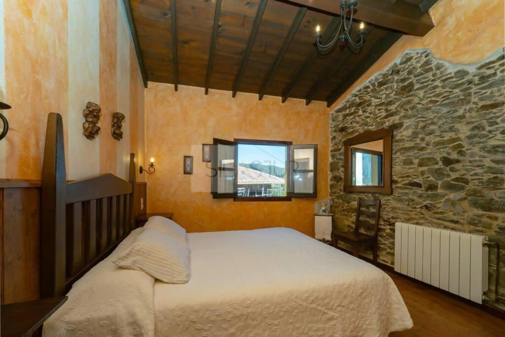 1 dormitorio con cama y pared de piedra en La Casona Del Cura I en Pravia