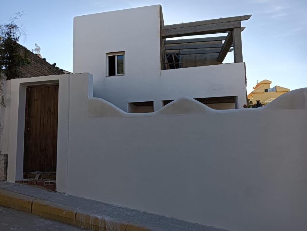 Casa blanca con puerta de madera y valla en Alhamar House with private pool, en Punta Umbría