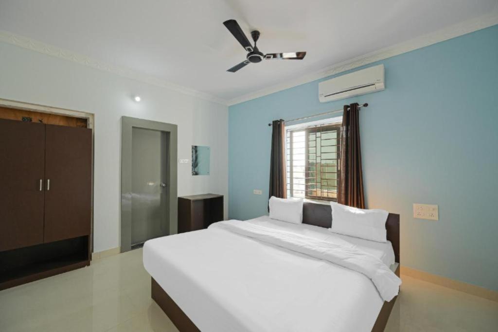 a bedroom with a white bed with a ceiling fan at Hotel Grace Premium Bhubaneswar in Bhubaneshwar