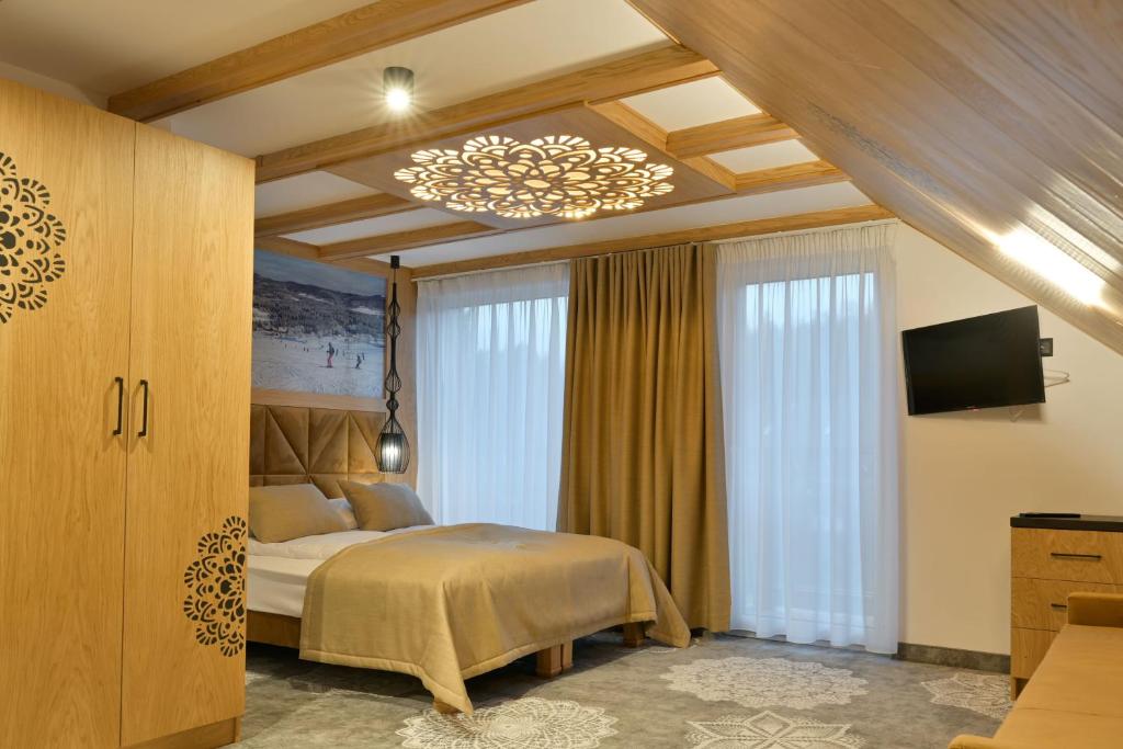 1 dormitorio con cama y lámpara de araña en Willa Zagroniówka, en Istebna