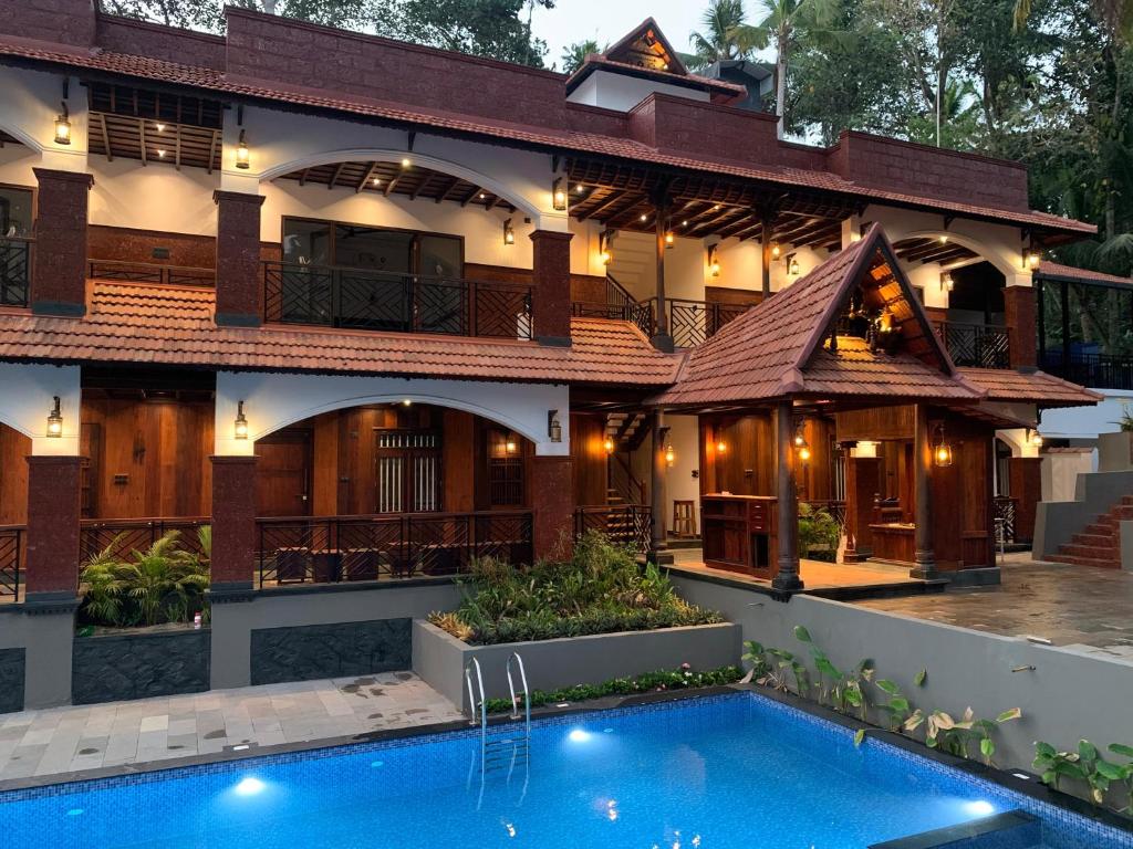 a house with a swimming pool in front of it at JEEVAN HOMESTAY kovalam in Kovalam