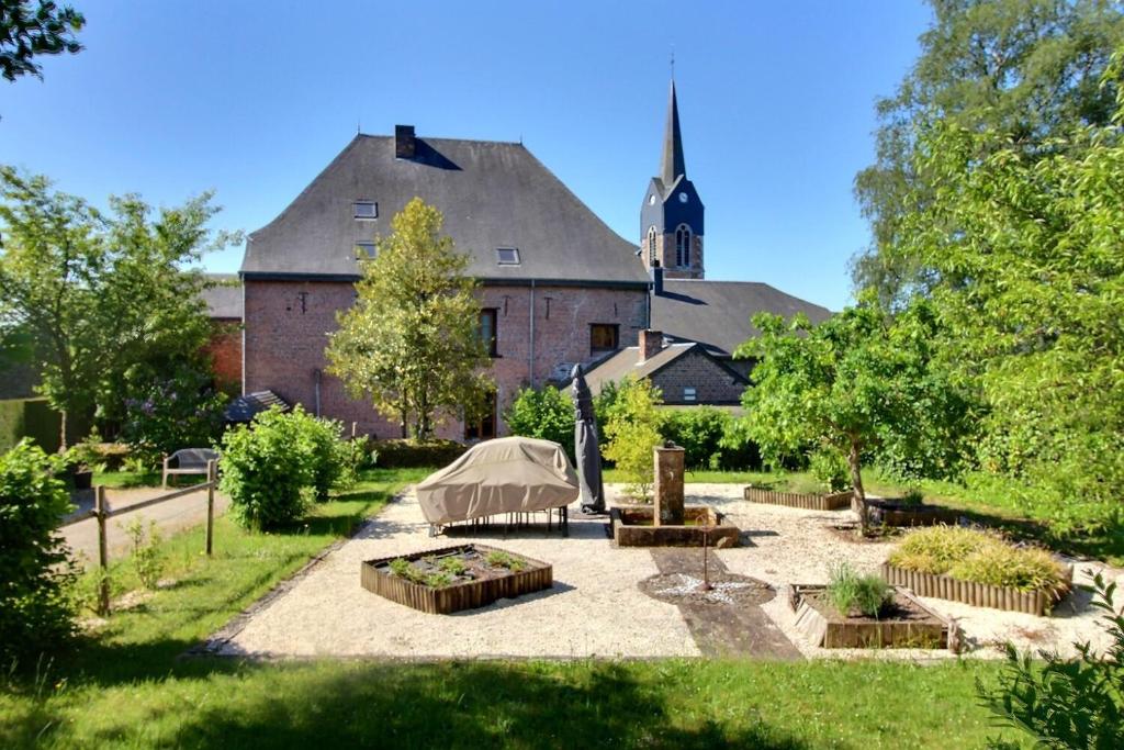 einen Garten vor einem großen Gebäude mit einer Kirche in der Unterkunft Château de Rienne in Gedinne