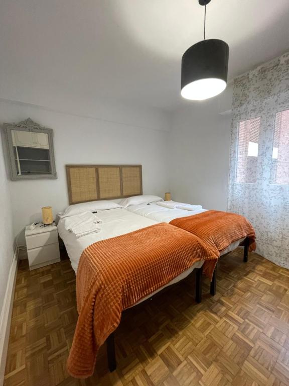 a bedroom with a large bed with an orange blanket at Apartamento en Getxo. Cercano al puerto viejo in Getxo