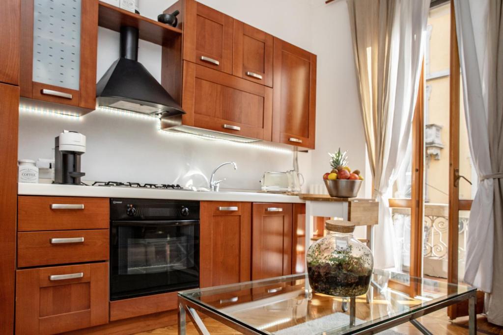 uma cozinha com armários de madeira e uma mesa de vidro em Appartamento milano, Bruna House em Milão