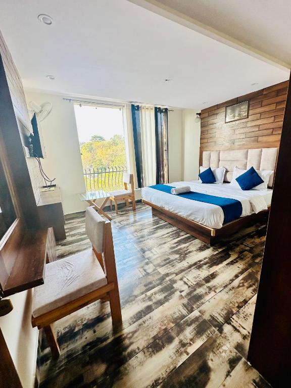 Schlafzimmer mit einem Kingsize-Bett und einem Stuhl in der Unterkunft Hotel Royal Orbit in Dehradun