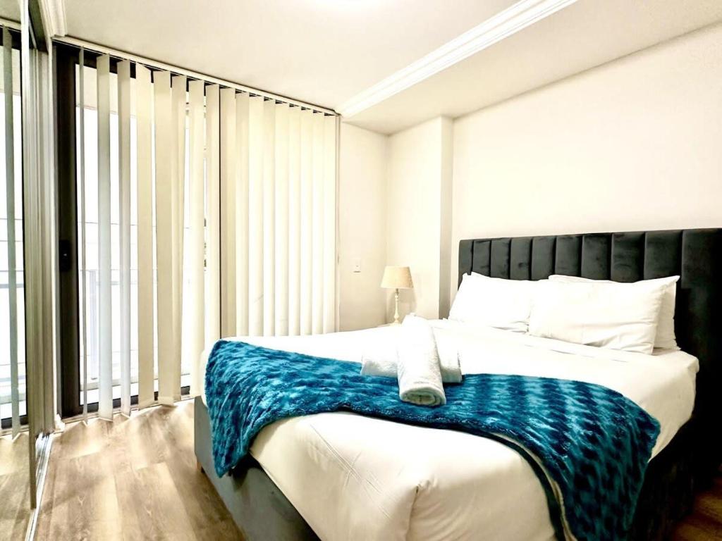 een slaapkamer met een bed met een blauwe deken erop bij Aircabin - Strathfield - Sydney - 2 Bedrooms Apt in Sydney