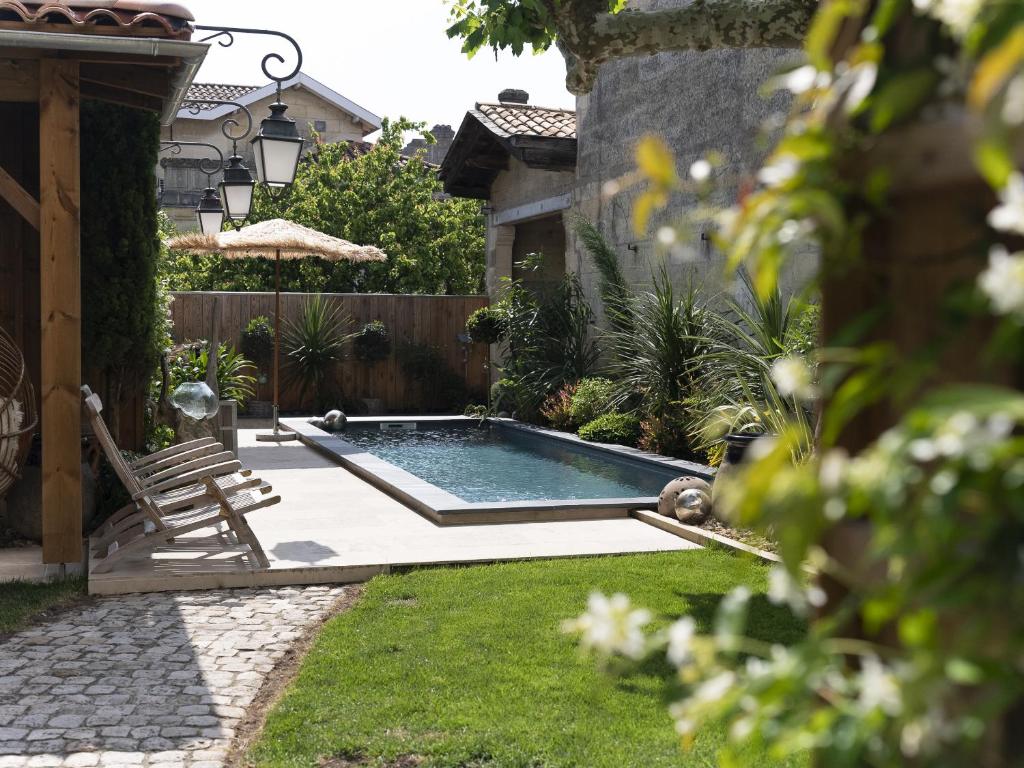 una piscina en un patio con una silla y una valla en La Maison Mulato en Libourne