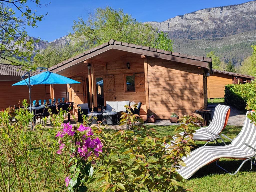 dos sillas y una sombrilla frente a una cabaña en Cabin No 7 Annecy Lake, en Demi-Quartier