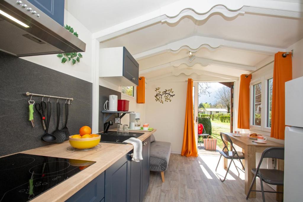 une cuisine avec des armoires bleues et un rideau orange dans l'établissement A La Rencontre Du Soleil - Camping, au Bourg-dʼOisans