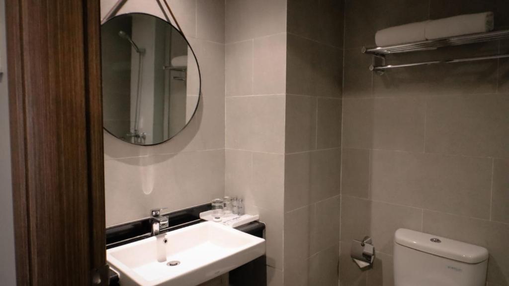 ein Badezimmer mit einem Waschbecken, einem Spiegel und einem WC in der Unterkunft Solia Hotel Yosodipuro in Solo