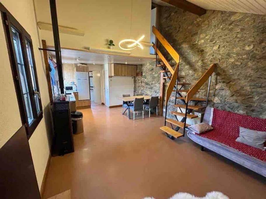 uma sala de estar com um sofá vermelho e uma parede de pedra em Appartement Duplex entre Genève et Lausanne em Saint-Livres